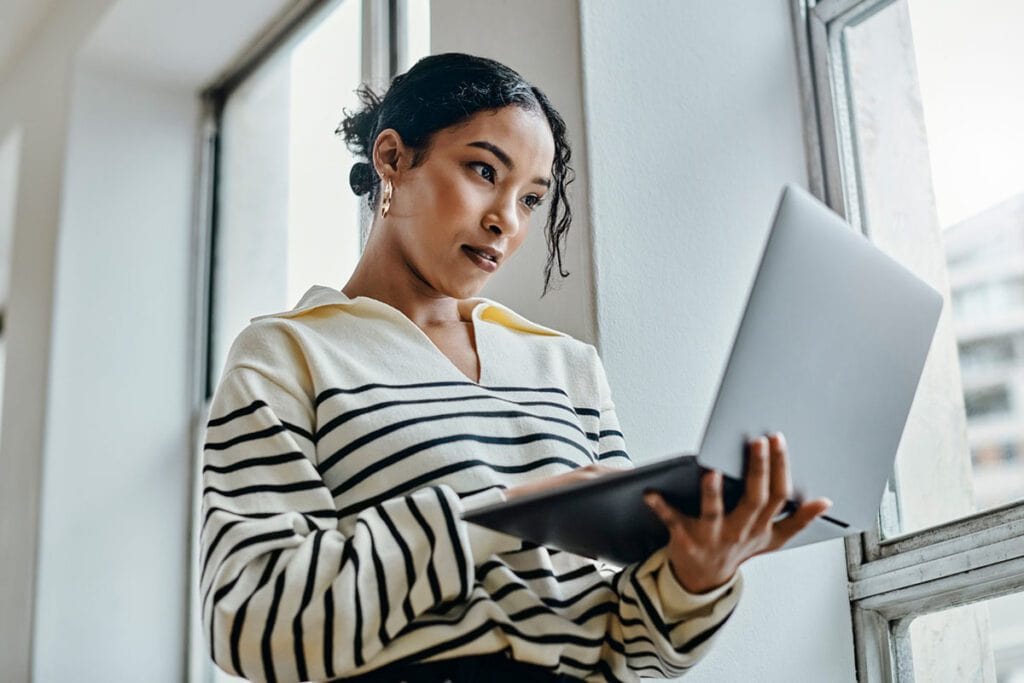 Black woman with laptop reading, typing and working for online digital newspaper, marketing or advertising company. Girl check email, post blog feedback or review social media content writing article